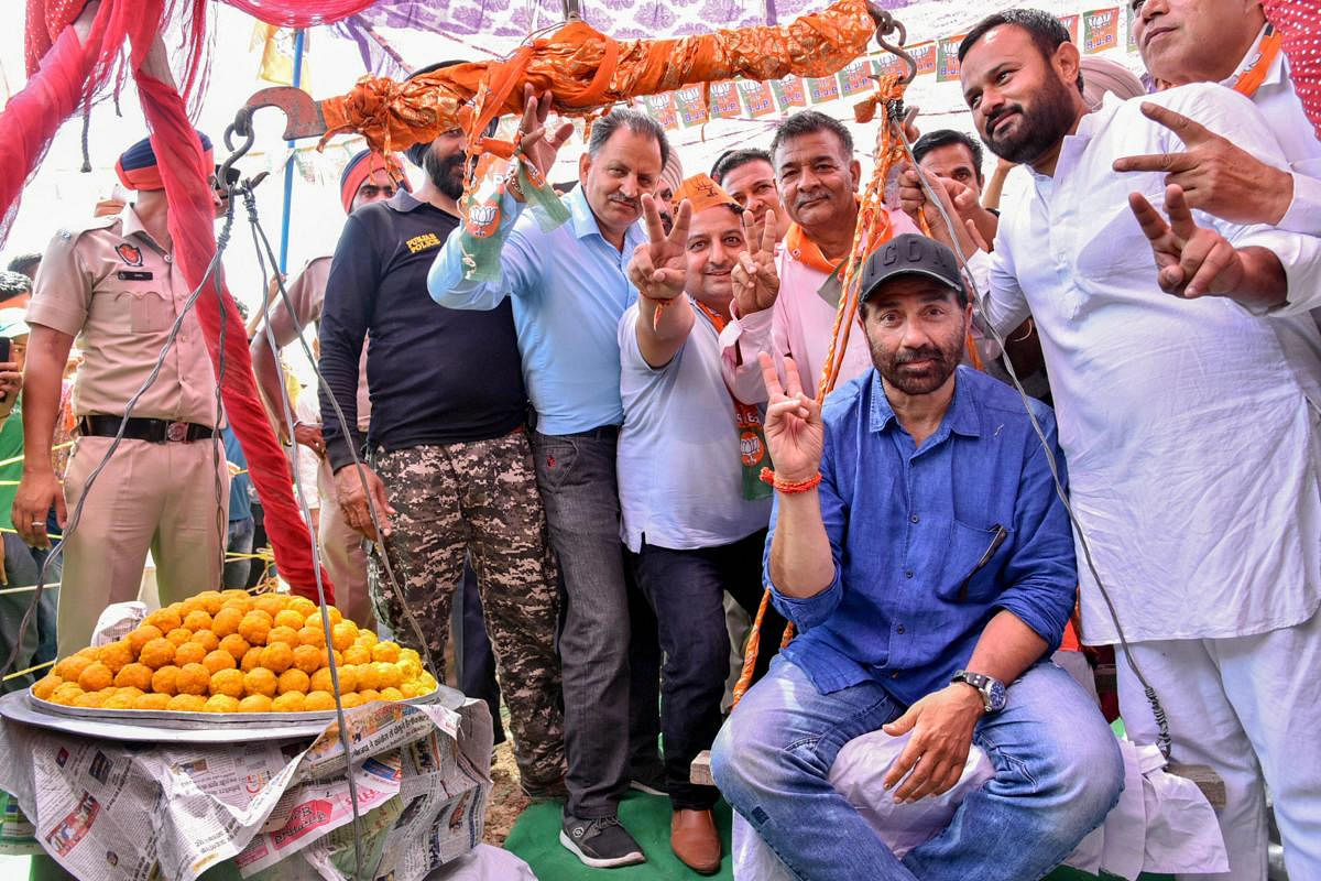 BJP candidate for Gurdaspur seat Sunny Deol sits on a weighing scale during his election campaign ahead of the last phase of Lok Sabha polls, in Pathankot, Sunday, May 12, 2019. (PTI Photo)