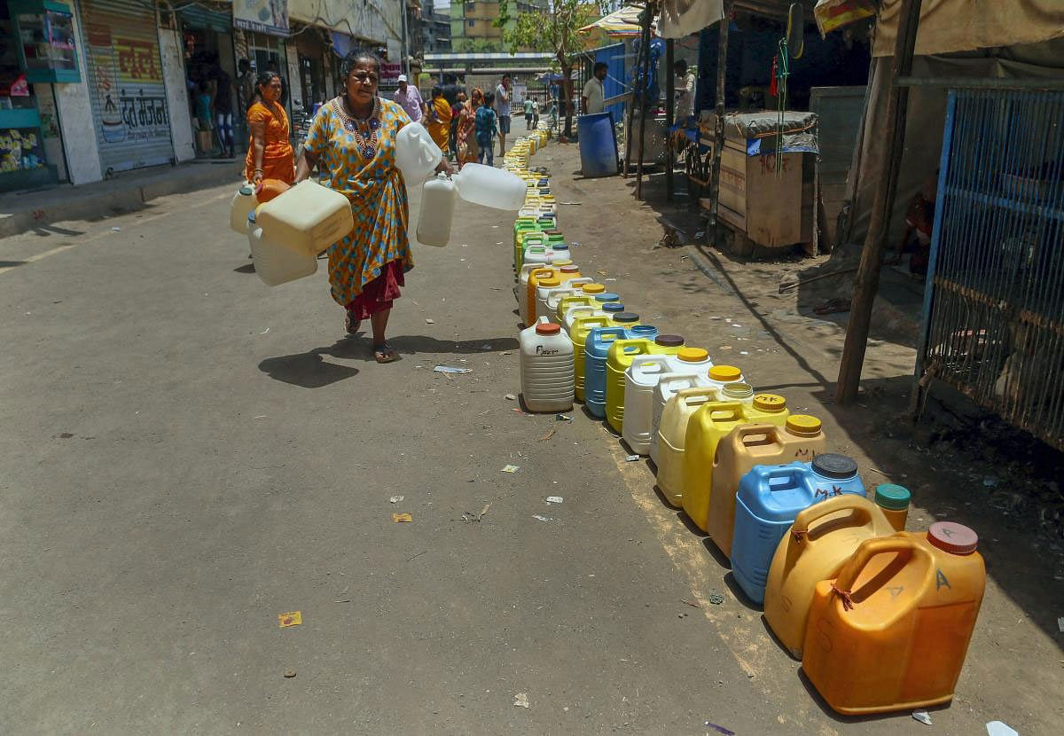 A woman walks along a long queue of plastic containers to collect water on a hot summer day, at Diva residential area in Thane, Thursday, May 16, 2019. (PTI Photo)