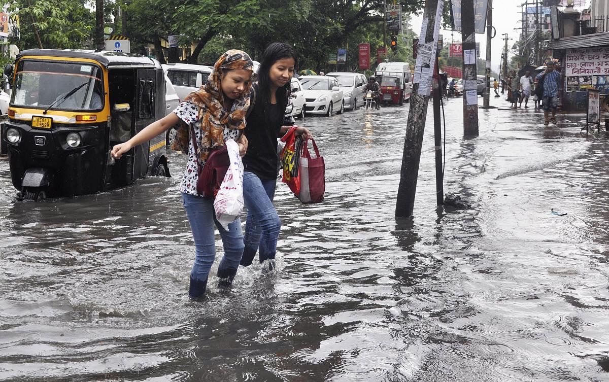 Commuters wade through a waterlogged street after heavy rainfall in Guwahati, Friday, June 14, 2019. PTI