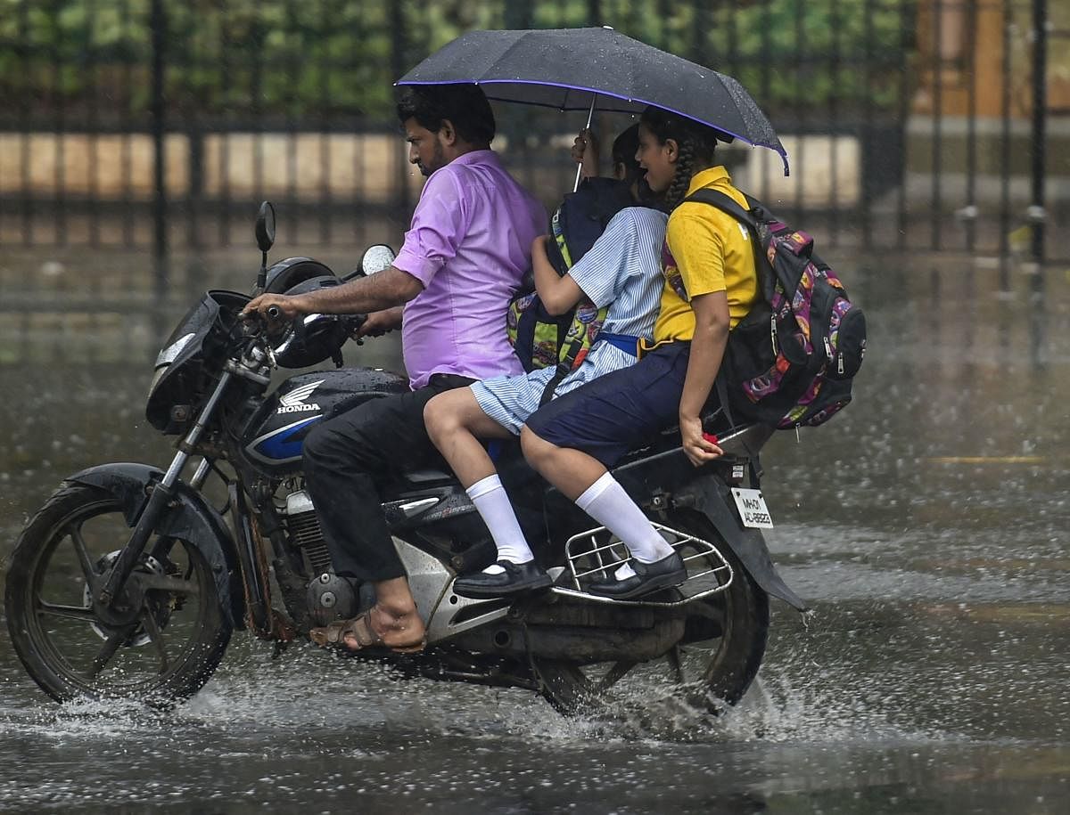 Students share an umbrella on a bike during heavy rainfall in Mumbai, Tuesday, June 18, 2019. PTI
