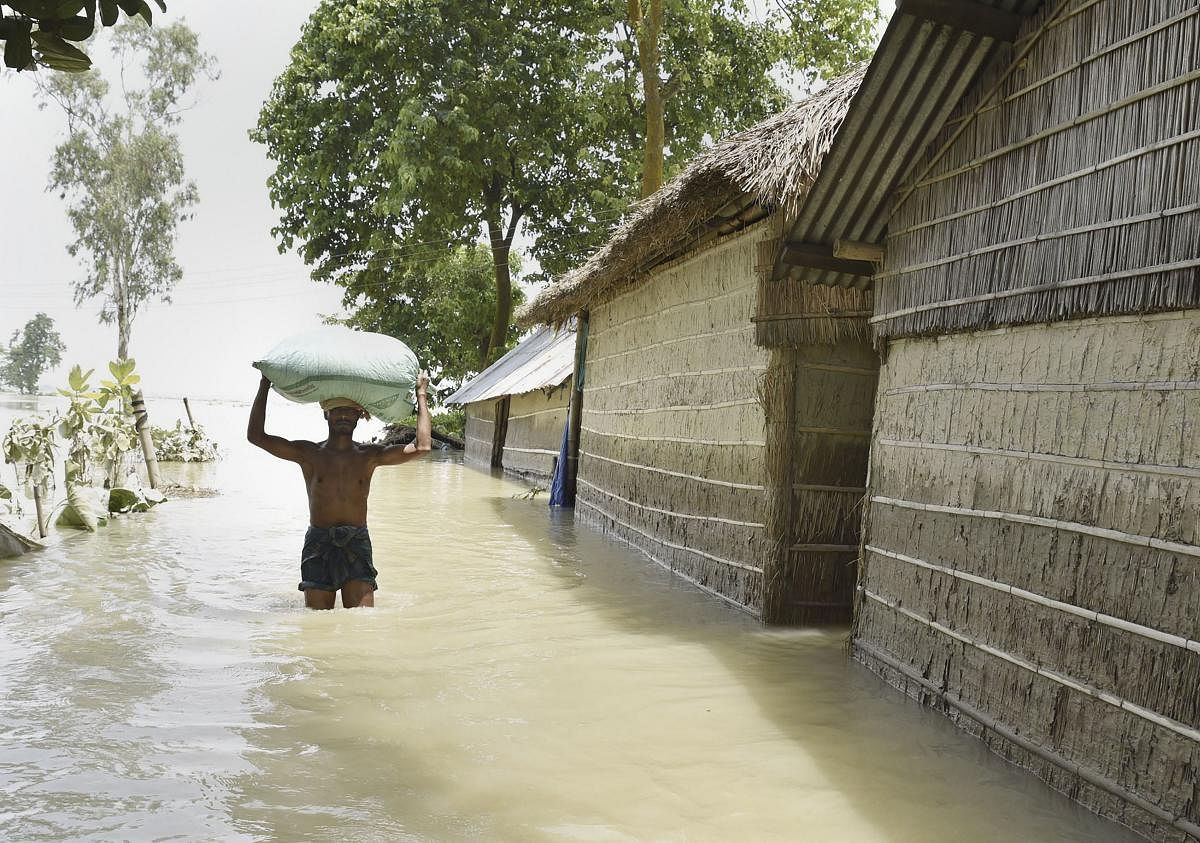 A man carries his belongings from a flood affected area to a safer place, in Morigaon district, Assam. (PTI Photo)
