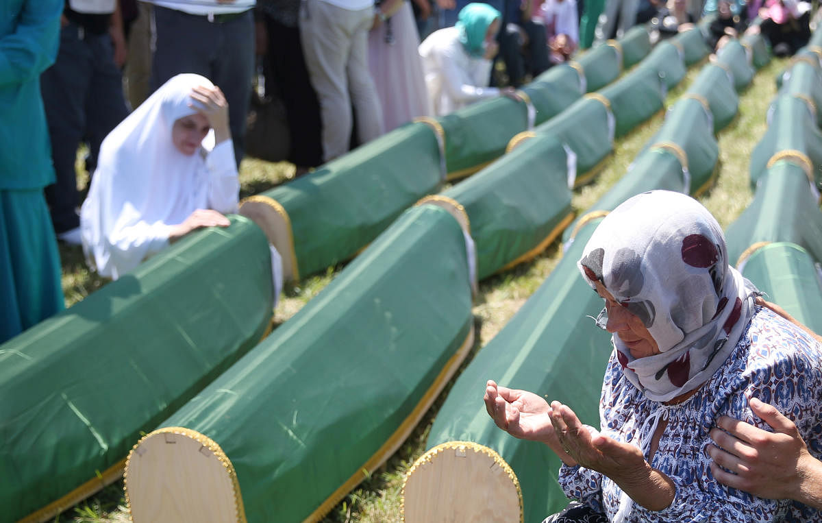 A Bosnian Muslim woman prays next to coffins during a mass funeral in the village of Kamicani, near Prijedor, Bosnia and Herzegovina. (Reuters Photo)