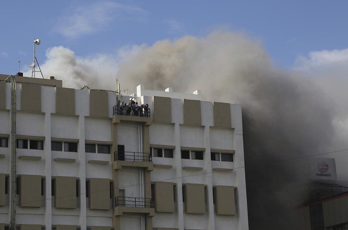 People awaiting rescue stand on the balcony of a nine-story building with offices of a state-run telephone company during a fire in Mumbai. (AP/PTI Photo)