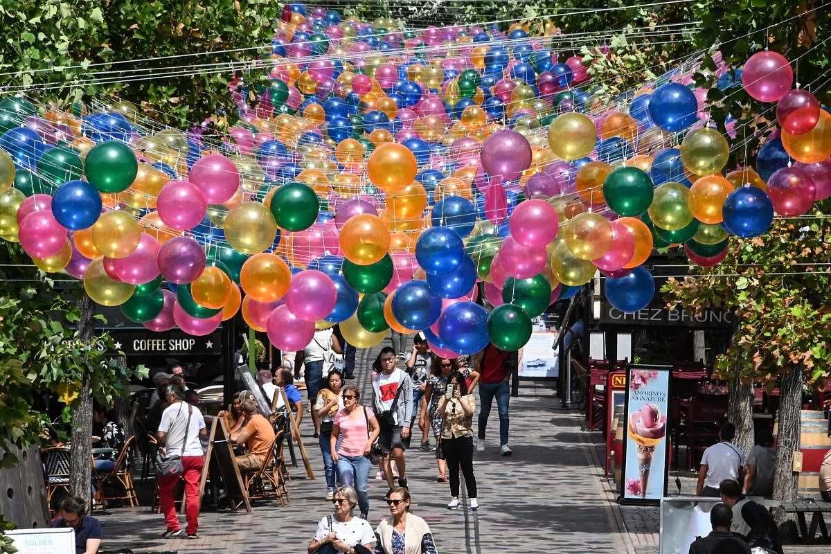 People walk under the installation of more of 3000 floating balloons called