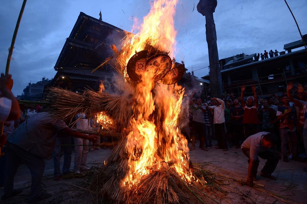 Nepali devotees watch as a straw effigy of Ghanta Karna burns during celebrations of the Hindu festival of
