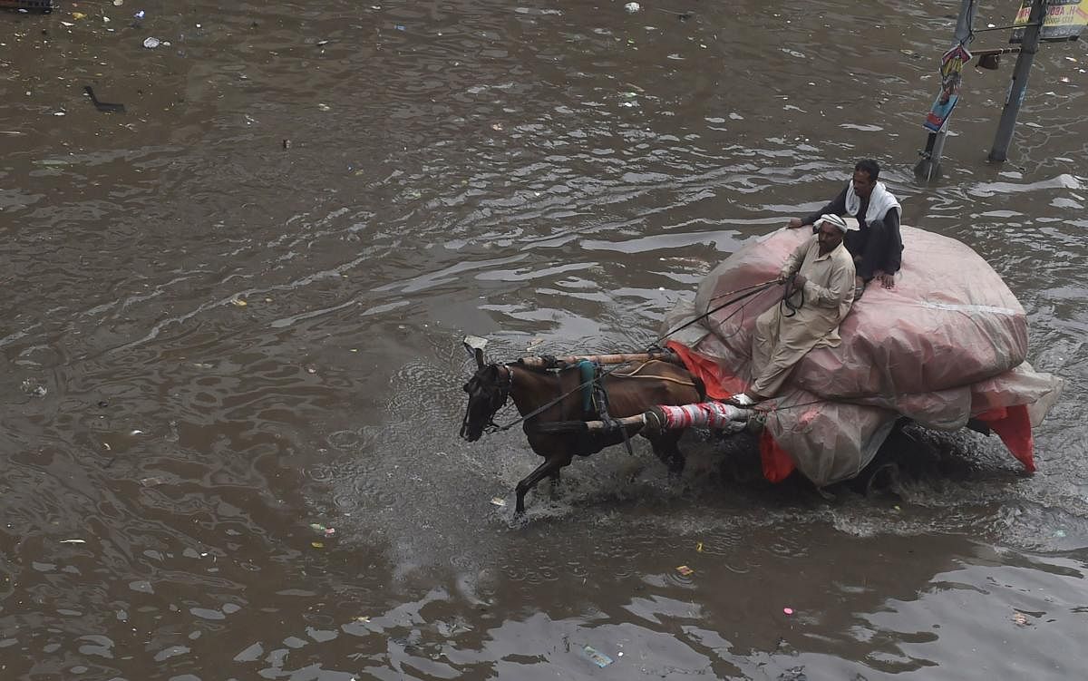 A man rides on his horse cart through a flooded street during heavy monsoon rains in Lahore. (Photo AFP)