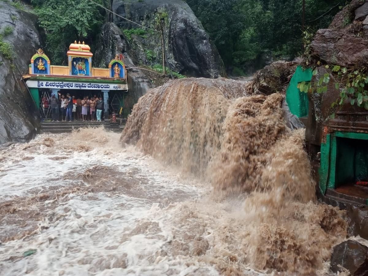 Stranded tourists inside Veerabhadreshwara Swamy Temple amid Kalhathagiri waterfalls in Tarikere. DH Photo