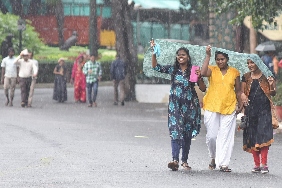 Girls covering by cloth to protect from rain at Lalbagh in Bengaluru on Thursday. (DH Photo | S K Dinesh)
