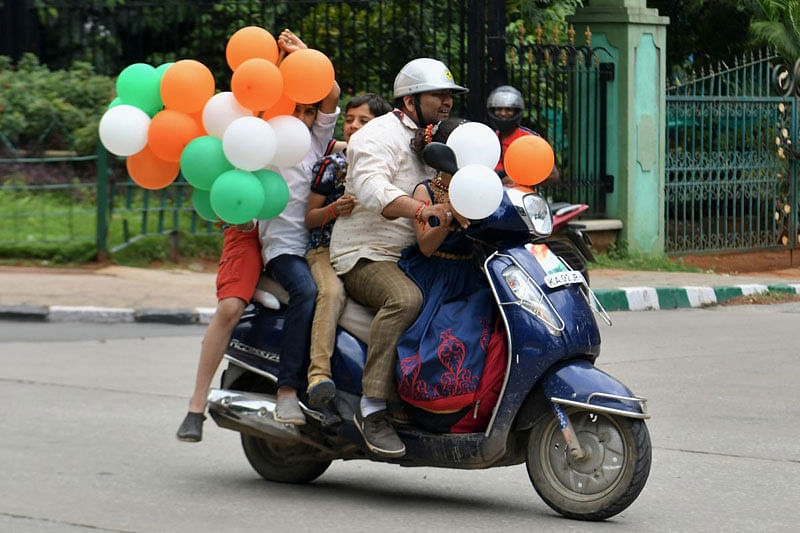 A family ride a scooter on the street as they hold balloons in the colours of the Indian flag during the India's 73rd Independence Day, August 15, 2019. (Photo: AFP)
