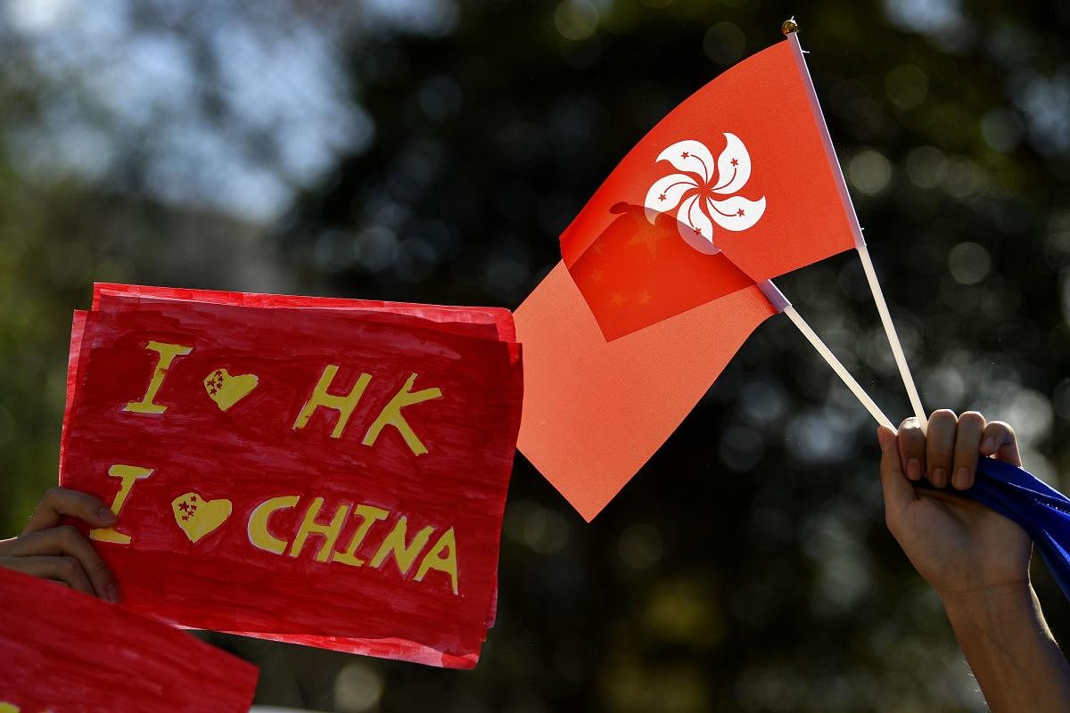 Pro-China activists hold up placards and China with Hong Kong flags while marching on the streets of Sydney on August 17, 2019 (AFP/Saeed KHAN)