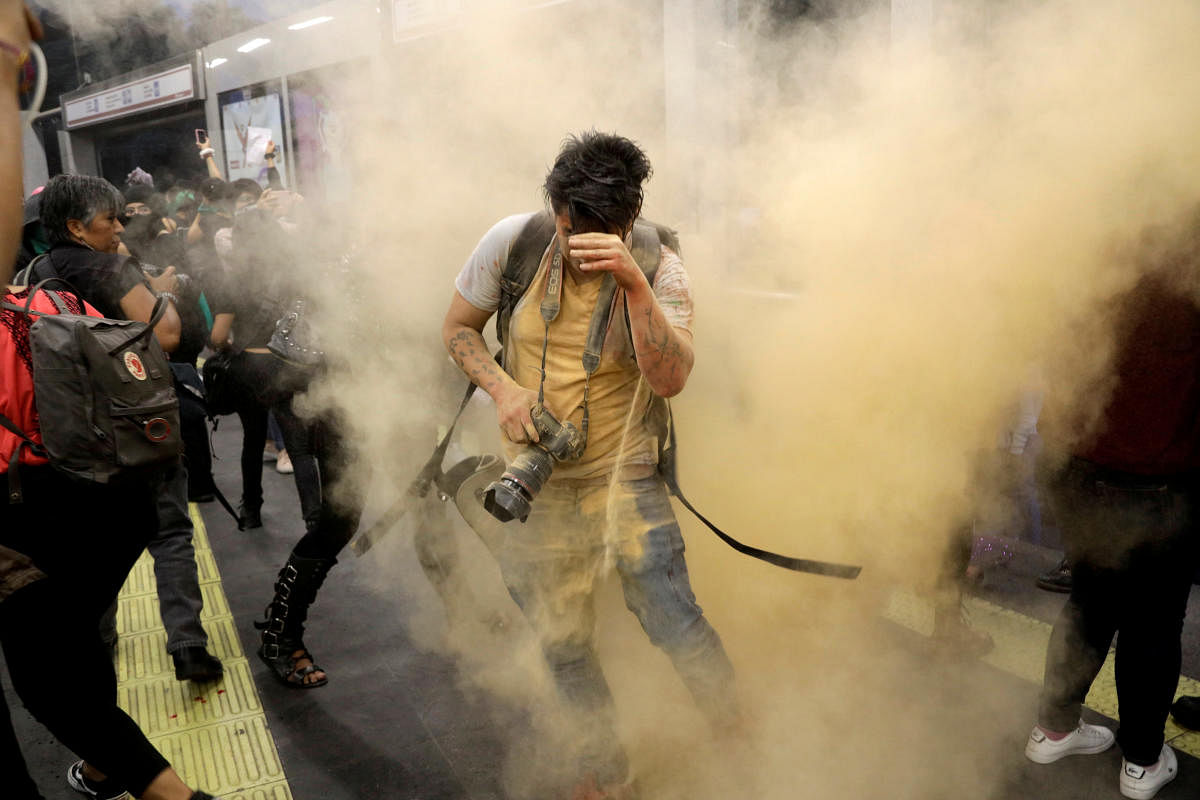 A photographer reacts as demonstrators throw coloured powder during a protest called