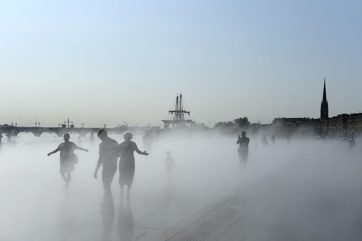 Tourists walk in a mist cloud on the water mirror in Bordeaux, southwestern France, on August 30, 2019 (AFP Photo)