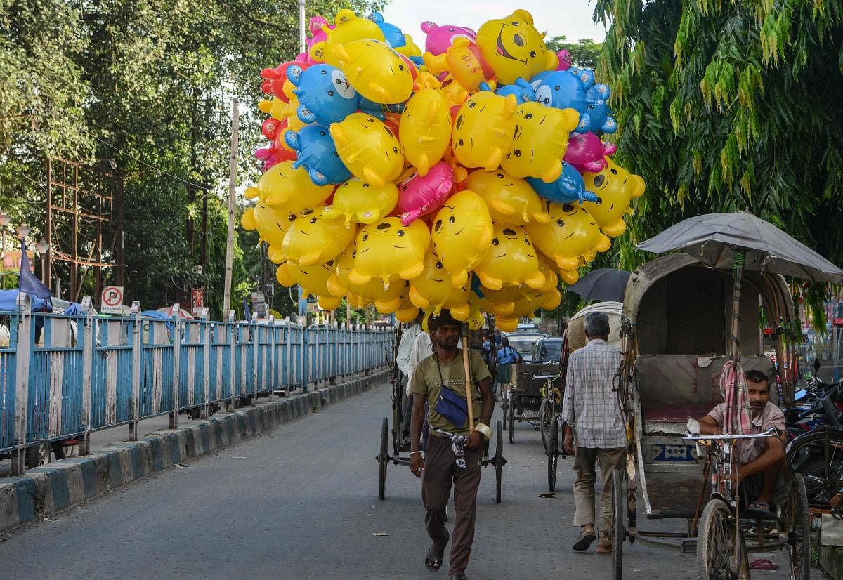 A vendor walks along the street carrying blow-up Winnie the Pooh toys he is selling in Siliguri on Septmeber 3, 2019. (AFP Photo)