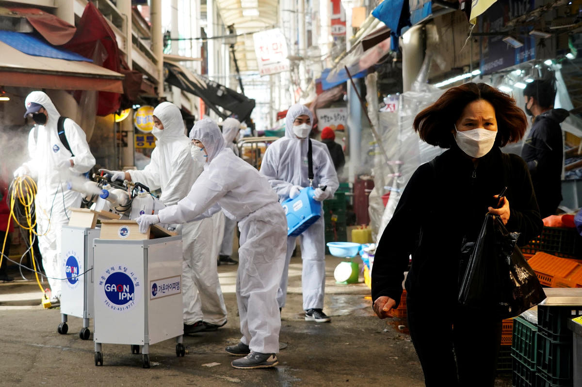 A woman wearing a mask to prevent contracting the coronavirus reacts as employees from a disinfection service company sanitize a traditional market in Seoul, South Korea. (Reuters photo)