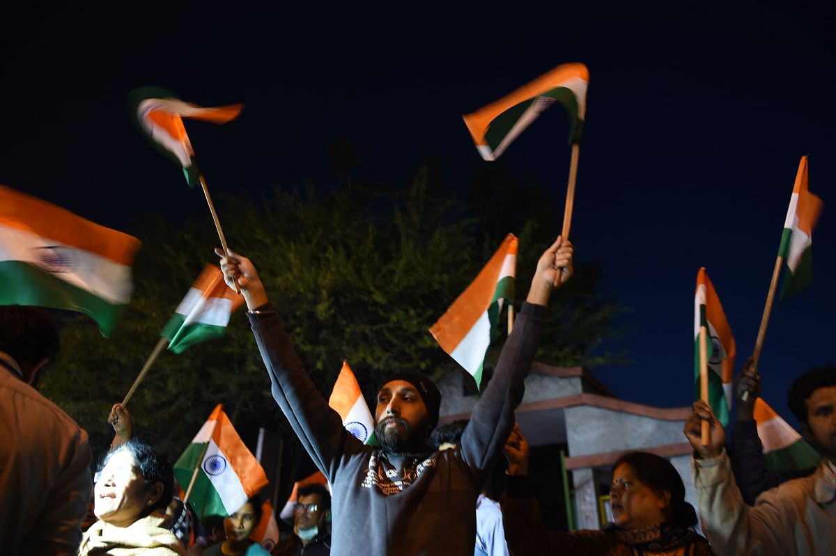 People wave national flags outside the gates of Tihar Jail after the execution of four men convicted in the gang-rape and murder of a student in 2012, in New Delhi (Credit: AFP)
