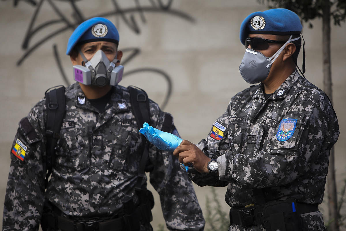 Soldiers wearing protective masks are deployed to provide security as workers of Ecuador's Ministry of Economic and Social Inclusion deliver food to low-income families at La Bota neighbourhood in northern Quito. (AFP Photo)