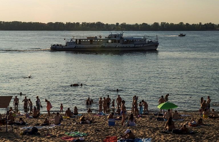 A tourist boat passes as people sunbathe at a beach on the Volga River in downtown Samara on August 23, 2017. AFP Photo