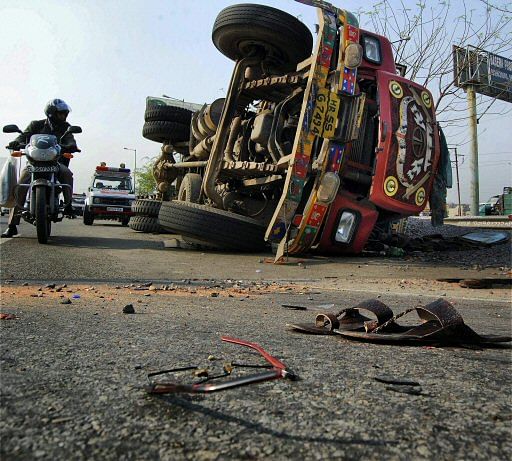 Slippers and broken glasses lying on the road as a high speed dumper overturned after hitting a bike at Noida expressway in Noida on Tuesday. PTI Photo