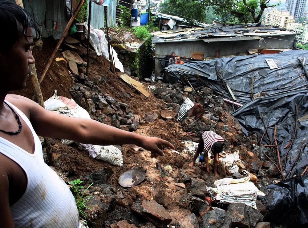 Residents look for belongings after a landslide on cluster of two slums at Kalwa in Thane, Mumbai on Tuesday. PTI