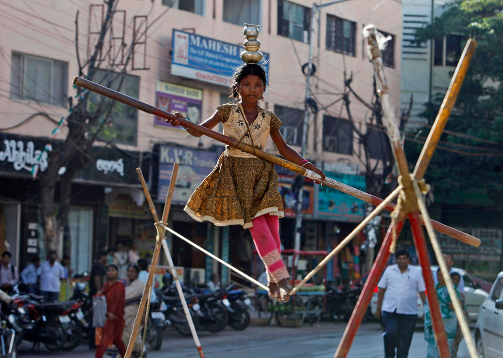 A child street artist walks a tightrope in Hyderabad, India, Tuesday, Aug. 28, 2012. The Indian cabinet has cleared a proposal that makes employment of children below 14-years old a cognizable offence with a maximum three years imprisonment or fine u...