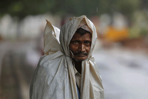 A man covers himself with plastic sheet to protect from the rain in  Hyderabad, India, Monday, July 22, 2013. The annual monsoon rains which  usually hit India from June to September are crucial for farmers whose  crops feed hundreds of millions of p...
