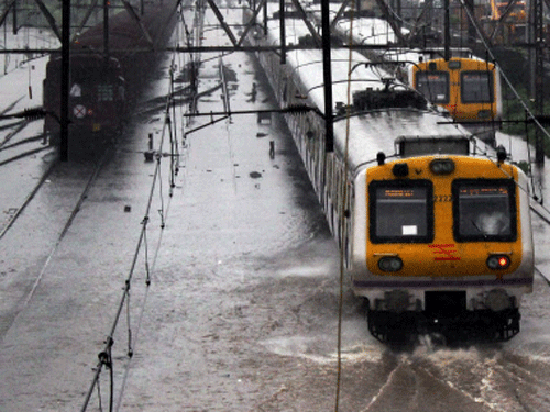 Local trains run through water-logged tracks after heavy shower in Mumbai on Tuesday. PTI Photo