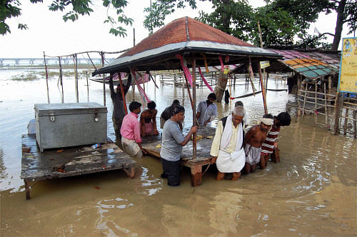 People push a chowki (priest's shelter) that was stuck in the flood  after heavy rains causing increase in water level of River Ganga in  Allahabad on Tuesday. PTI Photo