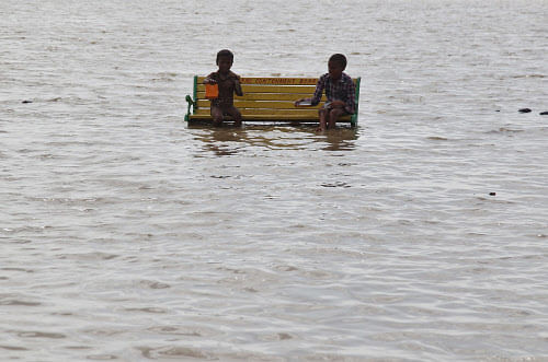 Boys play as they sit on a bench at the flooded banks of the river  Ganges after rains in the northern Indian city of Allahabad July 23,  2013. REUTERS