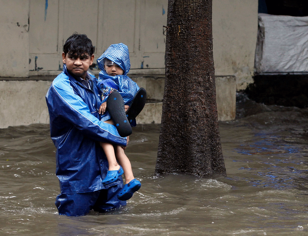 An unidentified man carries his son through the flooded street during heavy rain in Mumbai, India, Tuesday, July 23, 2013. (AP Photo/