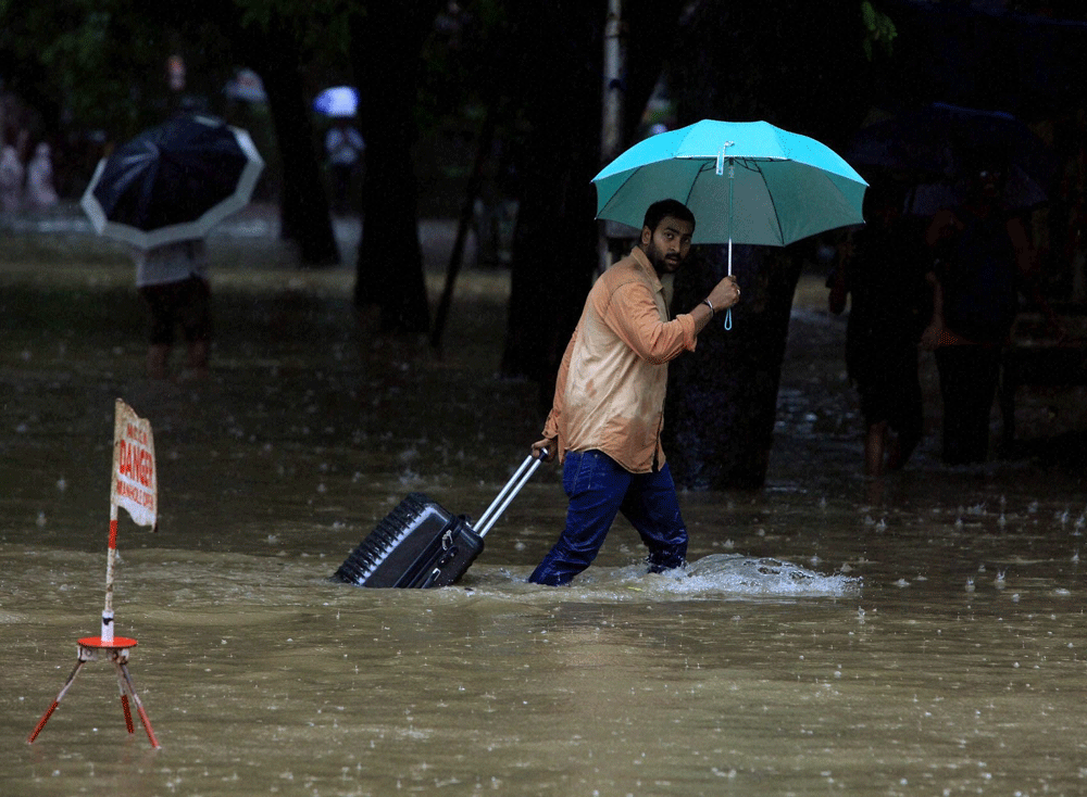 A man pulls his bag at a flooded street during showers in Mumbai on Tuesday. PTI Photo by Shashank Parade