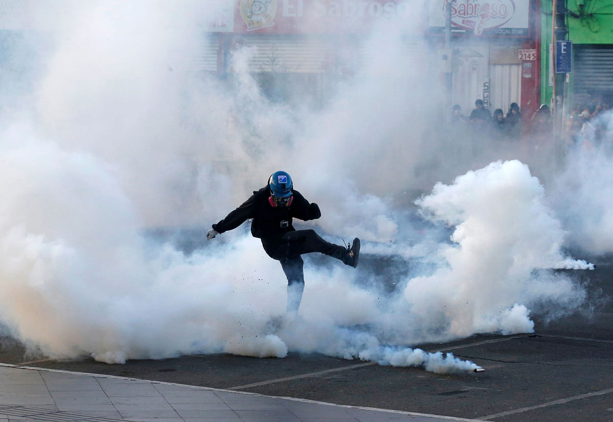 A protester kicks a tear gas canister during clashes at a rally on Women's Day celebrations in Valparaiso, Chile. (Credit: Reuters)
