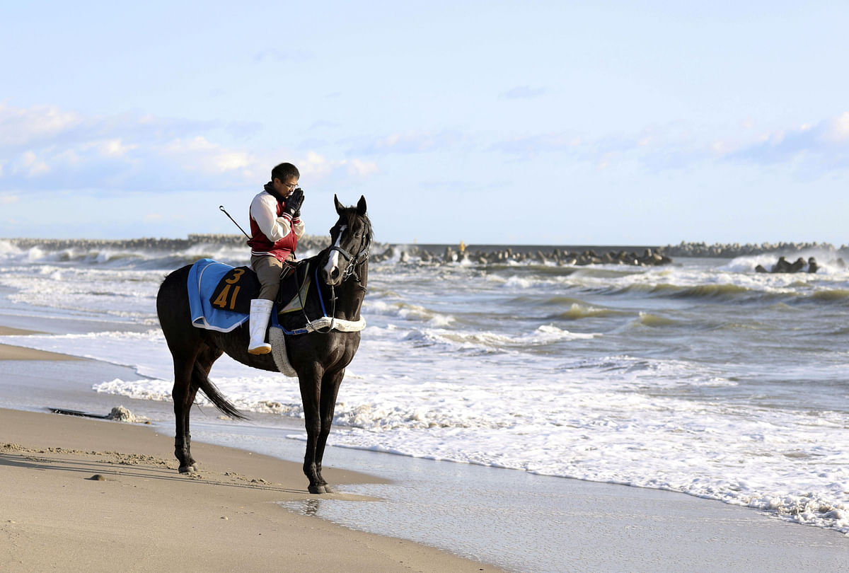 A man riding a horse prays towards the sea to mourn victims of the March 11, 2011 earthquake and tsunami disaster in Minamisoma, Fukushima prefecture, Japan. (Credit: Reuters/ Kyodo)