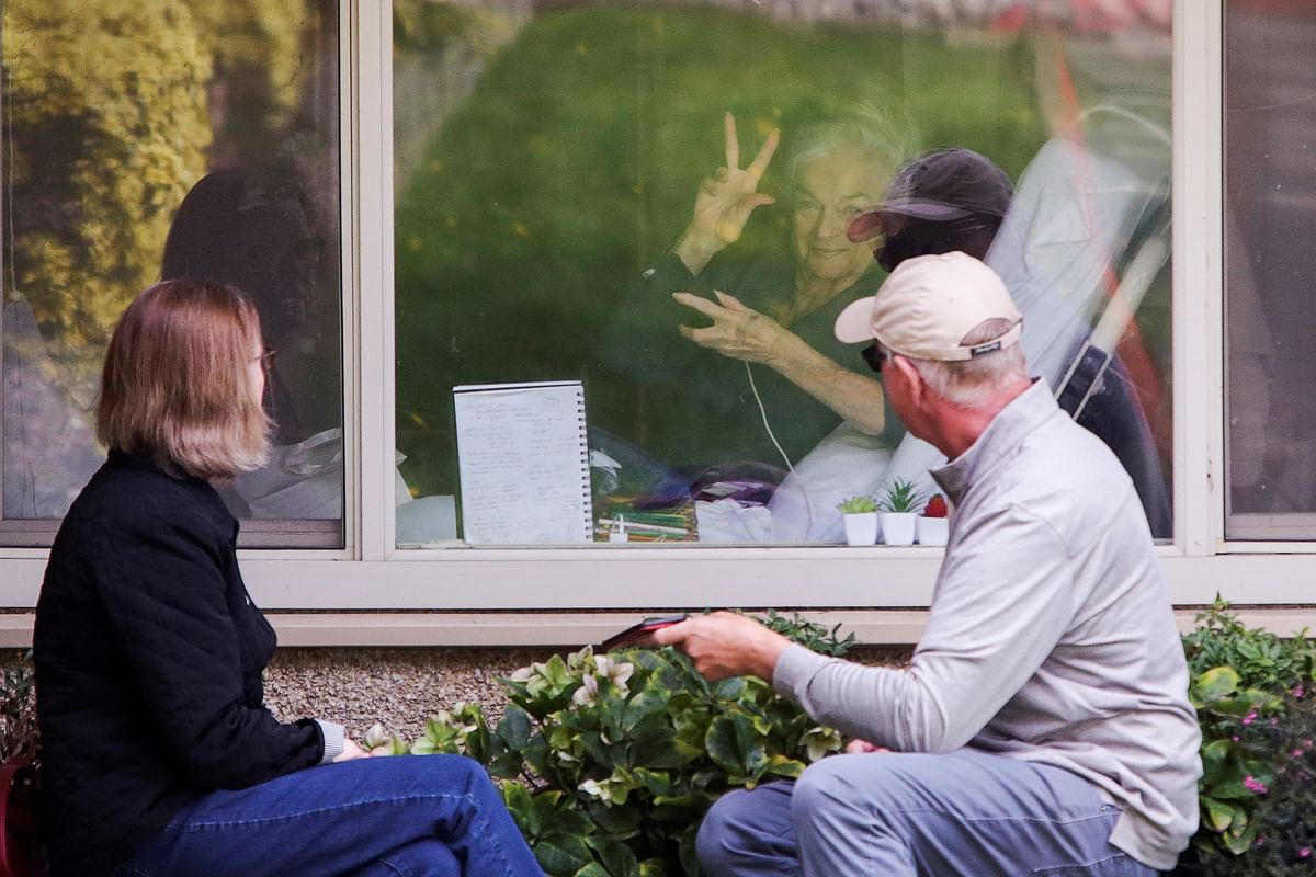 Judie Shape, 81, who tested positive for coronavirus, acknowledges press photographers gathered outside at Care Center of Kirkland, Washington. (Credit: Reuters)