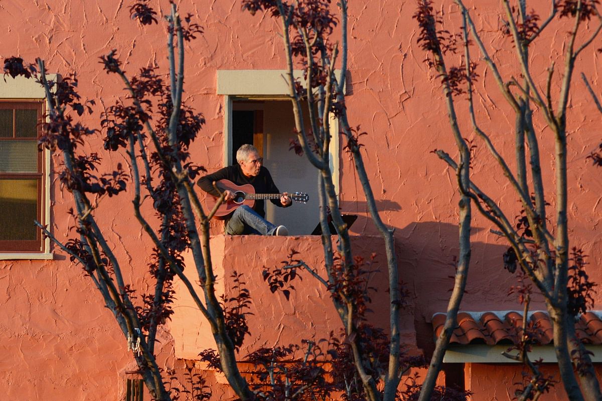Danny Wertheimer plays guitar and sings to his neighbors from his balcony two days after California’s Governor Gavin Newsom implemented a state wide