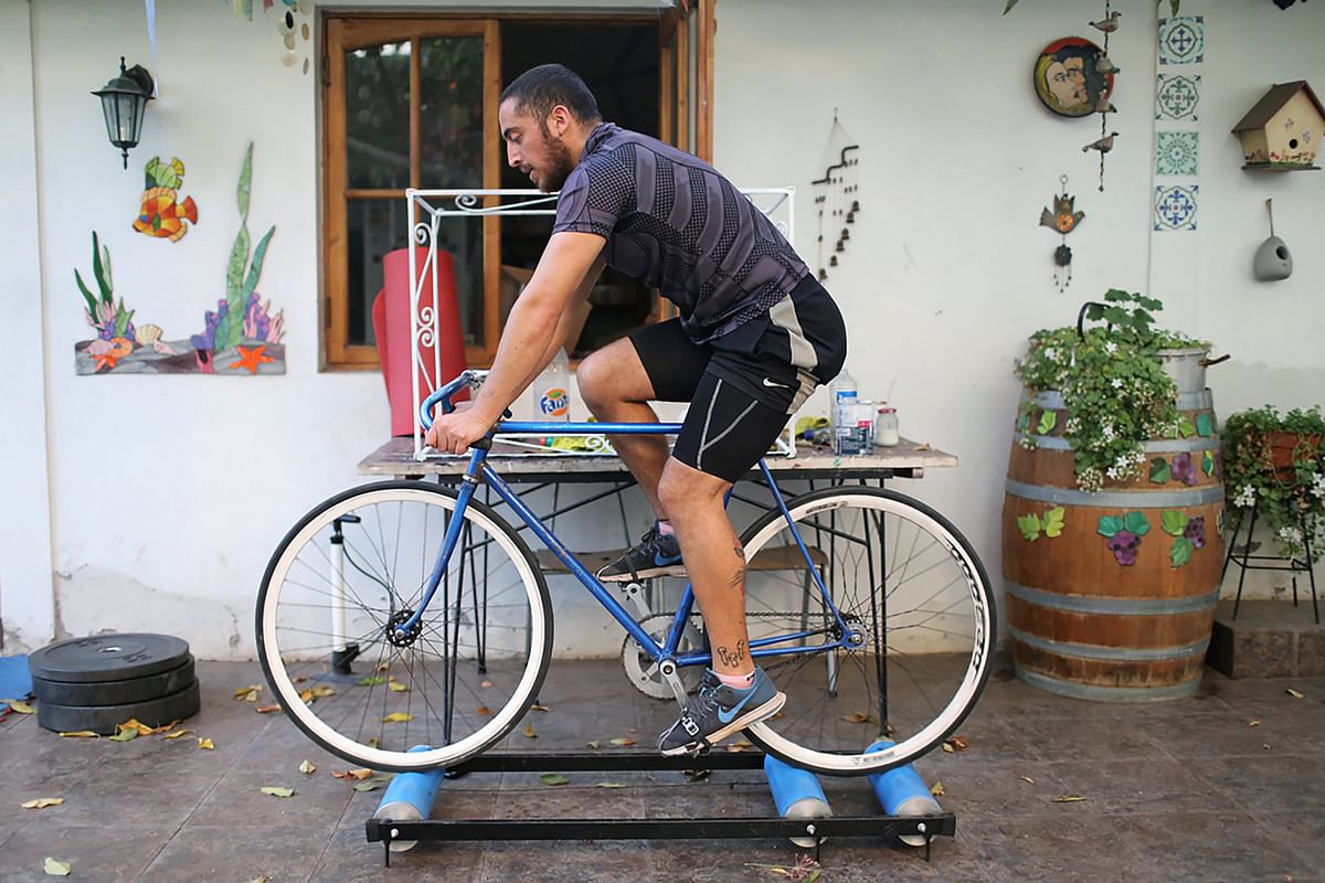 Fernando, uses a device to ride a bike while following an online physical activity program at his home yard after Chilean government announced a total quarantine for wealthy areas of the capital Santiago. (Credit: Reuters Photo)
