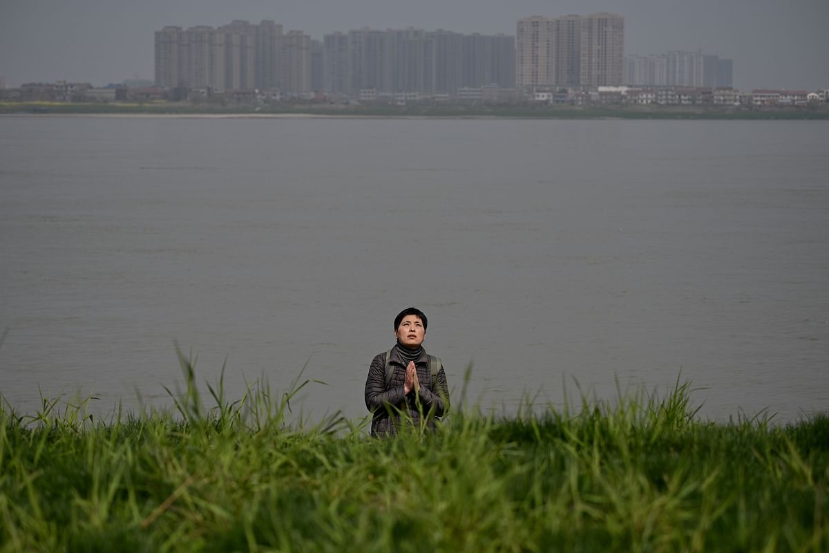A Buddhist woman prays before releasing turtles and fish into the Changjia river in Juijiang. (Credit: AFP)