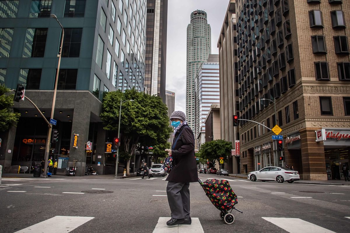 A woman wearing a mask walks in Downtown Los Angeles during the coronavirus (COVID-19) outbreak. (Credit: AFP)