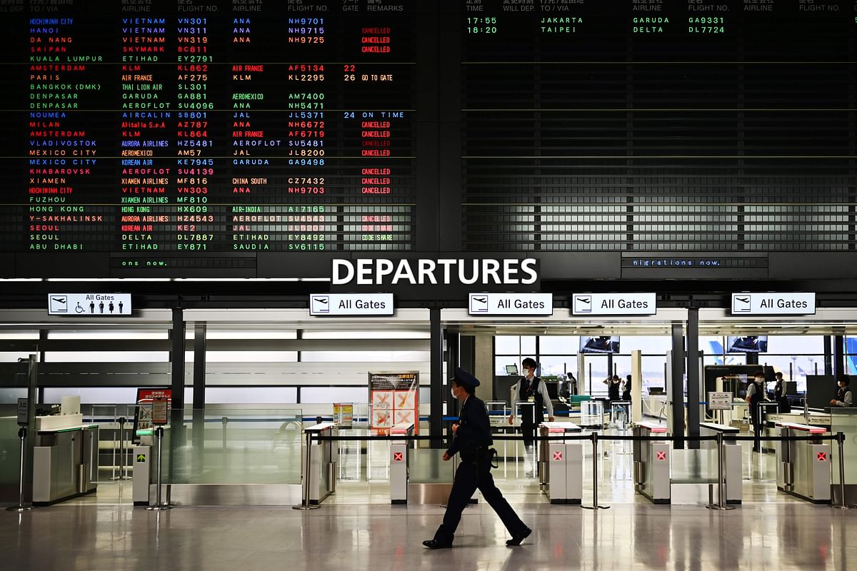 A security guard walks in front of a signboard showing cancelled flights at the departures area of the international terminal at Narita International Airport in Japan. (Credit: AFP Photo)