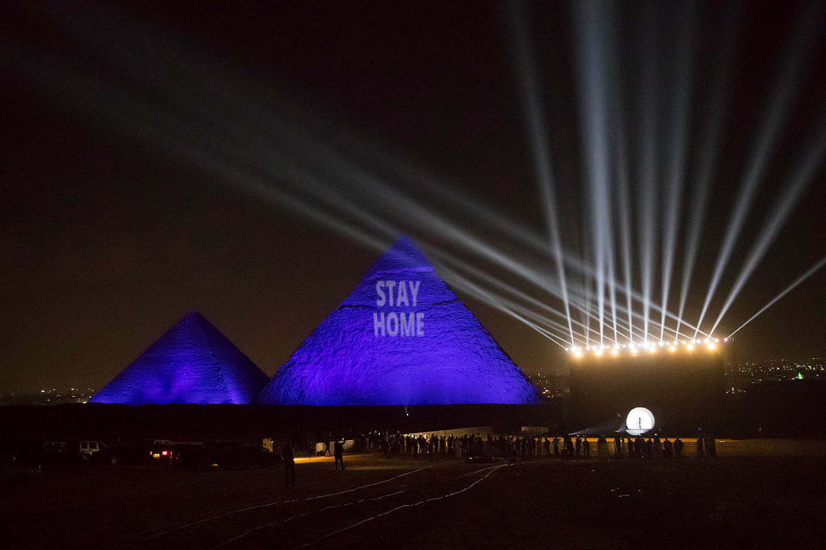 A picture taken on April 18, 2020 show the Great pyramids lighten-up with blue light and reading with a laser projection the message
