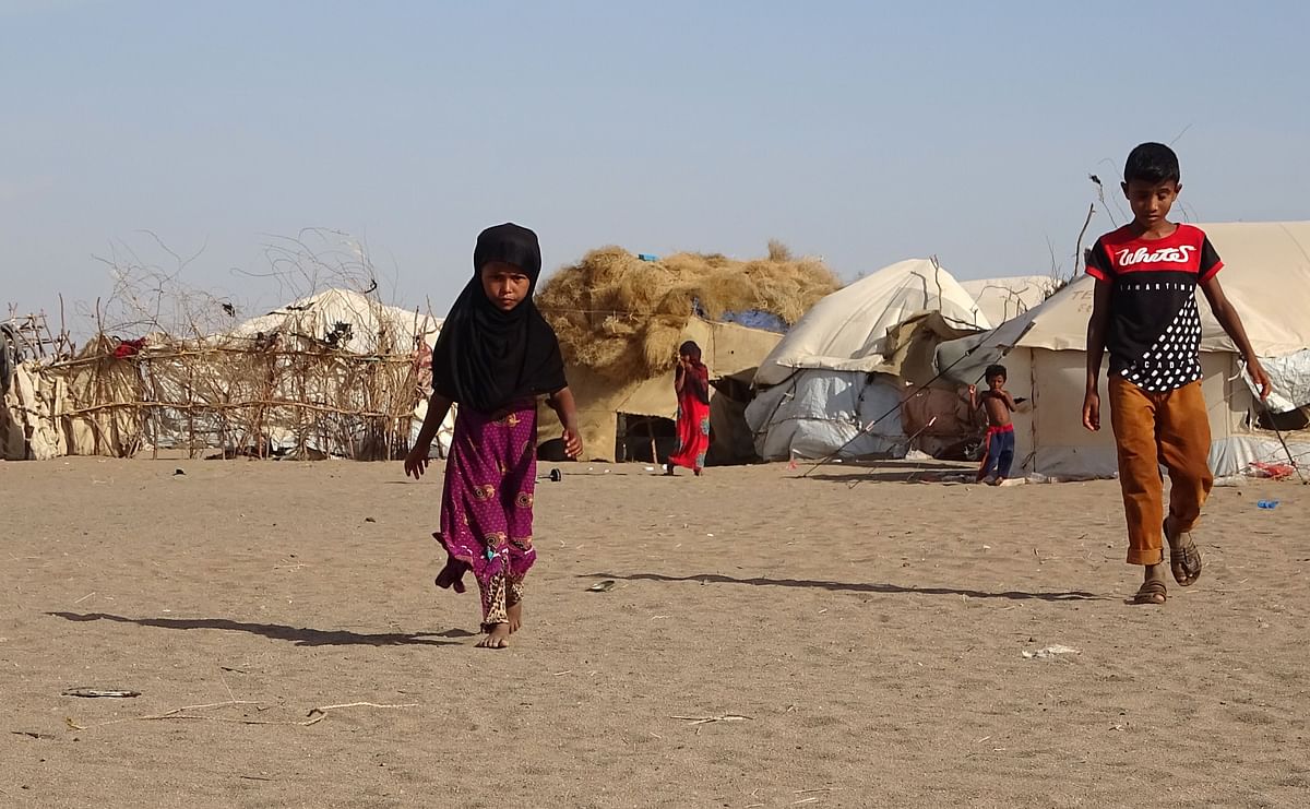 Children walk past tents at a displaced persons camp in the Khokha district of Yemen's western province of Hodeida. (Credit: AFP)