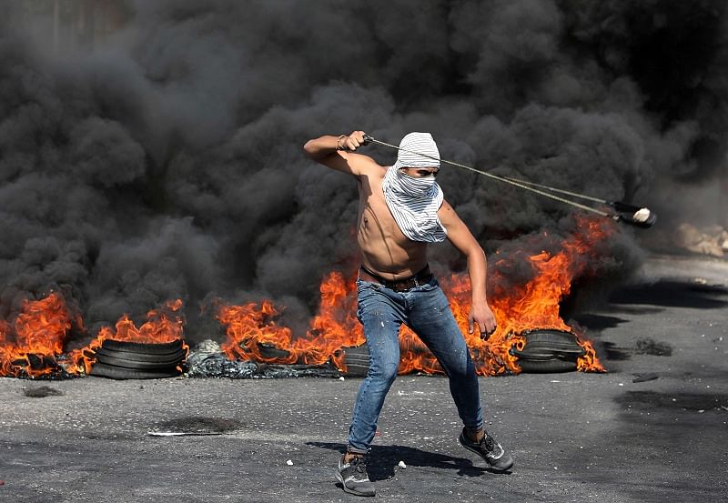 A Palestinian protester uses a slinghot to fire stones against Isreaeli security forces during clashes at the entrance of the West Bank city of Ramallah. (AFP)
