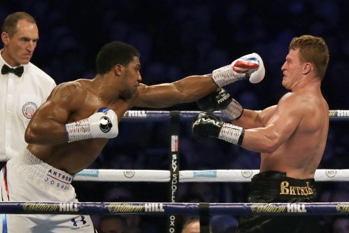 Russia's Alexander Povetkin (2nd L) falls backwards as Britain's Anthony Joshua (R) throws a punch to knock him to the canvas in the 7th round during their boxing world Heavyweight title fight at Wembley Stadium in north west London on September 22, 2018. - Britain's Anthony Joshua retained his International Boxing Federation, World Boxing Association and World Boxing Organisation heavyweight titles with a seventh-round stoppage of Alexander Povetkin at London's Wembley Stadium on September 22, 2018. AP PTI