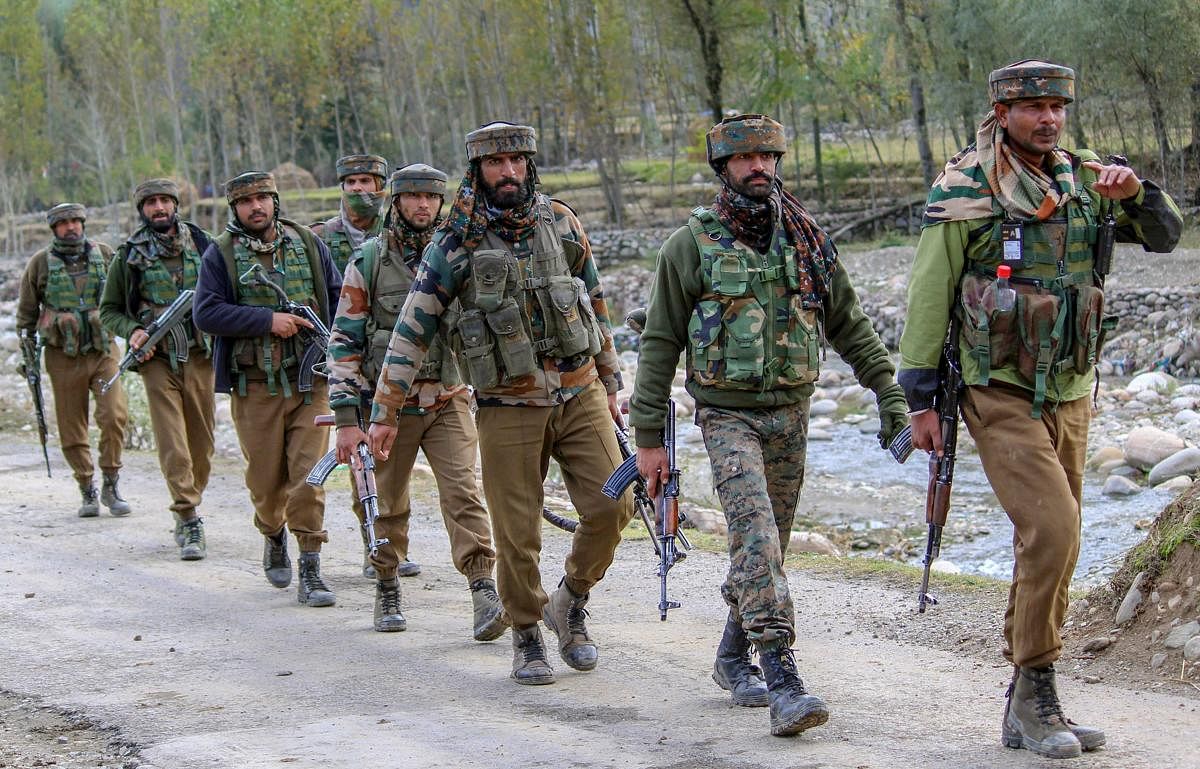 Army soldiers walk towards the house where top Hizbul Mujahideen commanders were hiding during an encounter in which PhD scholar-turned-militant Mannan Wani was killed, in Handwara.(PTI photo)