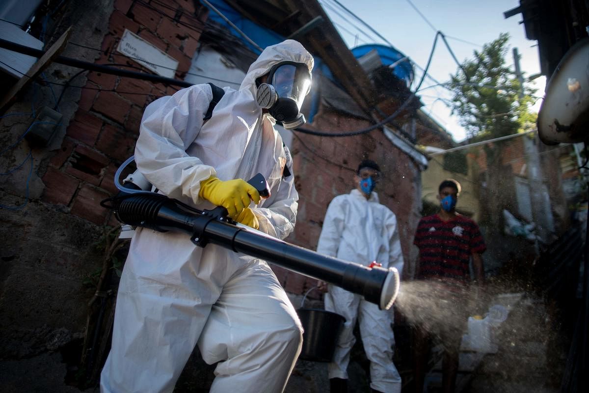 Volunteers disinfect an alley at the Santa Marta favela in Rio de Janeiro, Brazil, during the COVID-19 coronavirus pandemic on April 20, 2020. - Brazil's President Jair Bolsonaro said Monday he wants quarantines imposed by several state governors lifted this week, despite health ministry warnings that the coronavirus pandemic has yet to peak there. Credit: AFP Photoa