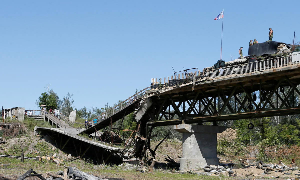 Local residents cross a bridge, which was exploded during a military conflict on the contact line between forces of the separatist Luhansk People's Republic and Ukrainian armed forces, as members of the self-proclaimed republic's emergencies ministry dismantle fortifications in Stanytsia Luhanska settlement, Ukraine August 26, 2019. (REUTERS/Alexander Ermochenko)