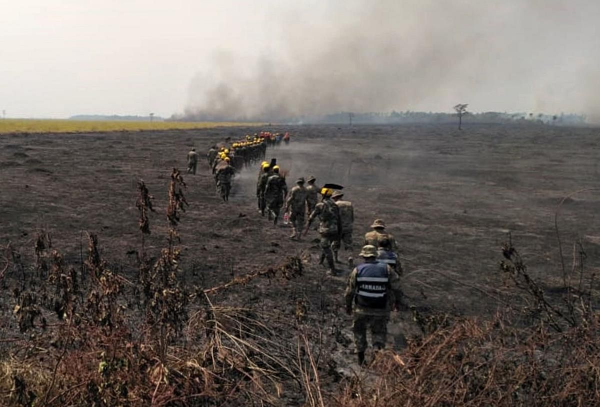Firemen walk through a burnt field as they combat a fire in the surroundings of Robore in eastern Bolivia, on August 22, 2019. (STR / AFP)
