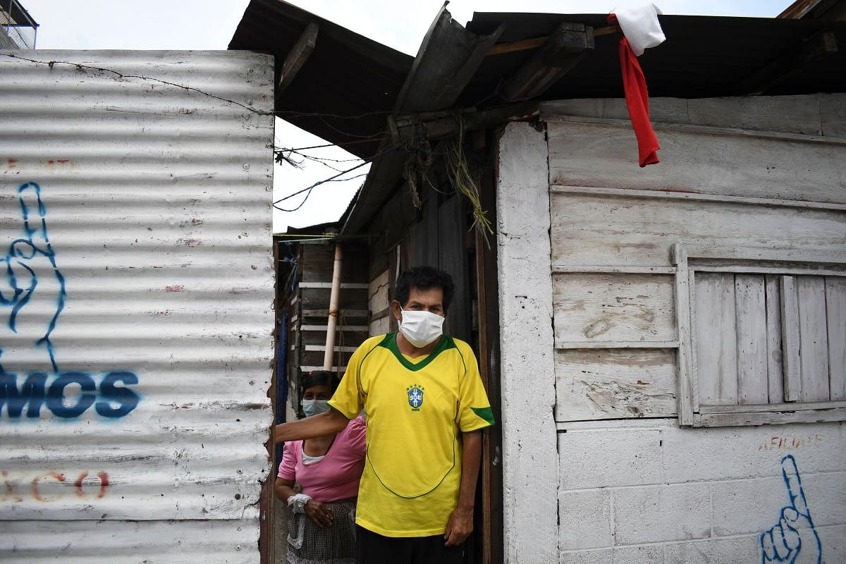 A man stands at his door, where he has hung a white and a red flag as a signal he needs to be delivered food (white) and medicines (red), at La Brigada neighbourhood in Guatemala City. (AFP Photo)