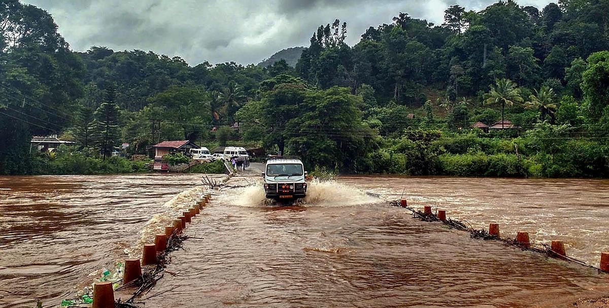 A vehicle passes through a bridge with overflowing water of Bhadra River, near Chikmagalur in Karnataka on Monday. PTI Photo