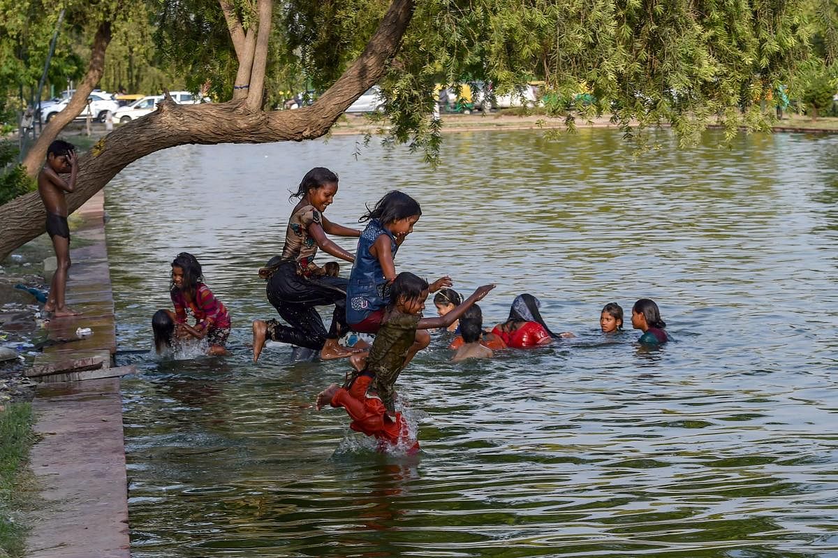 Children beat the heat in the waters at the India Gate Boat Club, as the mercury rises, in New Delhi on Saturday. PTI Photo