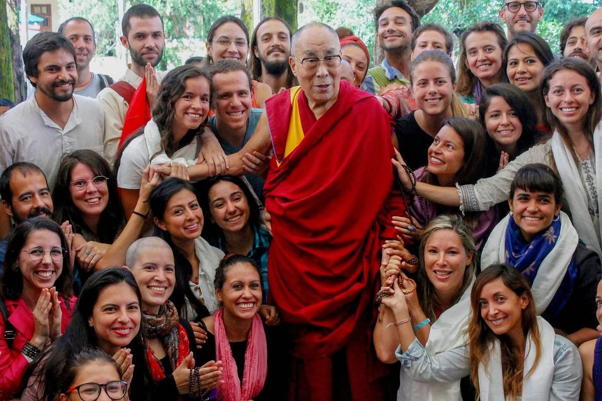 Tibetan spiritual leader the Dalai Lama with a group of Indian and foreign tourists at Tsuglagkhang Temple in Mcleodganj, near Dharamshala on Saturday. PTI Photo